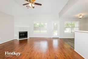Magnolia house for rent - A spacious living room with a fireplace and a ceiling fan.