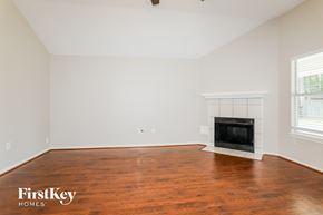 Magnolia house for rent - A large empty room with a fireplace and wooden floors.