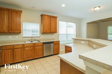 Jacksonville house for rent - a kitchen with wooden cabinets and white counter tops and a sink