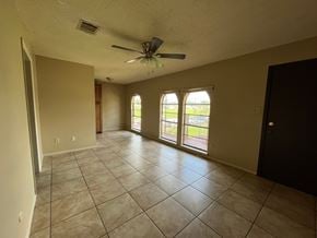 Bay City house for rent - A spacious room with a ceiling fan and large windows.