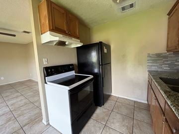 Bay City house for rent - A black refrigerator stands in a kitchen next to a stove.