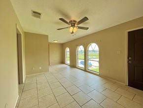 Bay City house for rent - an empty living room with a ceiling fan and tiled floors