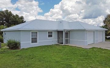 Lehigh Acres house for rent - A white house with a grey roof and a green lawn in front.
