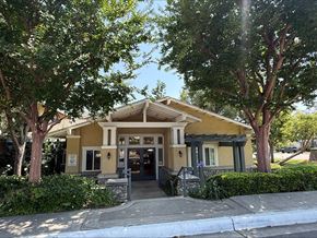 Claremont multi-family for rent - A yellow building with a black door and windows is surrounded by trees.