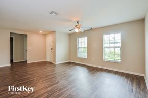 Deltona house for rent - A spacious room with wooden floors and a ceiling fan.