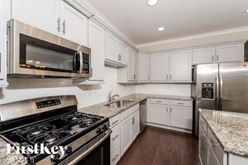 Gardendale house for rent - a white kitchen with stainless steel appliances and marble counter tops