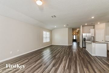 San Antonio house for rent - A spacious room with wooden floors and a kitchen area in the background.