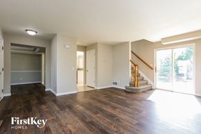 Parker house for rent - A spacious room with wooden floors and a staircase leading to another room.