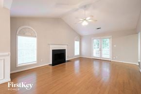 Suwanee house for rent - A spacious room with a fireplace and a ceiling fan.