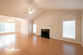 Suwanee house for rent - A spacious living room with a fireplace and a ceiling fan.