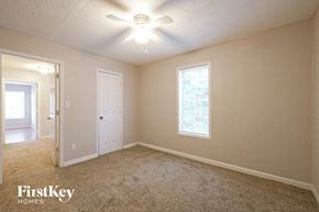 Suwanee house for rent - A room with a carpet floor, a ceiling fan, and a window with a view of trees.