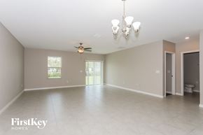 Riverview house for rent - A spacious room with a chandelier, ceiling fan, and a window.