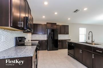 Riverview house for rent - A kitchen with a black refrigerator and a FirstKey Homes logo.