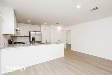 Converse house for rent - a kitchen and living room with white cabinets and wood flooring