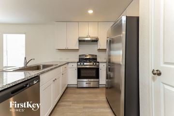 Converse house for rent - A modern kitchen with a stainless steel refrigerator and white cabinets.