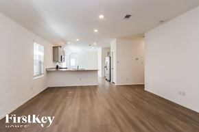 New Caney house for rent - A spacious room with wooden flooring and white walls, with a kitchen area visible in the background.