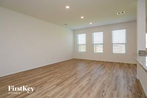 New Caney house for rent - A spacious room with wooden flooring and three windows.