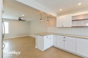 Tucson house for rent - A kitchen with white cabinets and a fan on the ceiling.