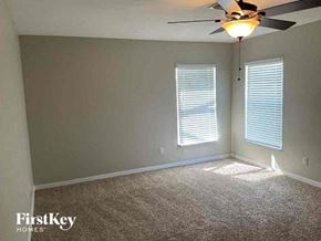 Cape Coral house for rent - A room with a carpet floor, a ceiling fan, and two windows with blinds.