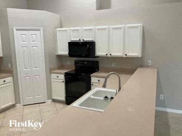 Cape Coral house for rent - A kitchen with white cabinets and a black stove top oven.
