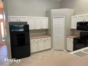 Cape Coral house for rent - A kitchen with white cabinets and black appliances.
