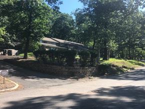 Harrisburg apartment for rent - A tree-lined street with a stone wall and a house in the background.