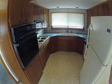 Longmont apartment for rent - A kitchen with a black oven and a white fridge.