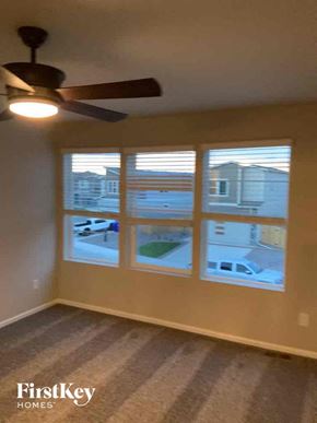 Colorado Springs house for rent - a living room with three windows and a ceiling fan