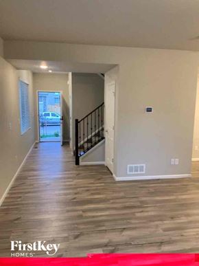 Colorado Springs house for rent - an empty living room and hallway with wood floors and a staircase