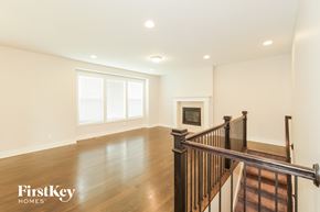 Raymore house for rent - A spacious room with wooden floors and a staircase leading to the upper level.