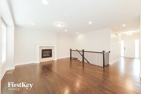 Raymore house for rent - A spacious living room with a fireplace and wooden floors.