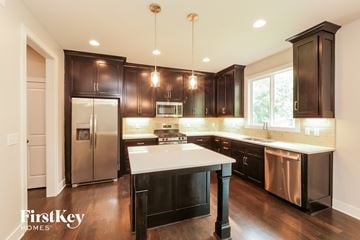 Raymore house for rent - A modern kitchen with dark wood cabinets and stainless steel appliances.
