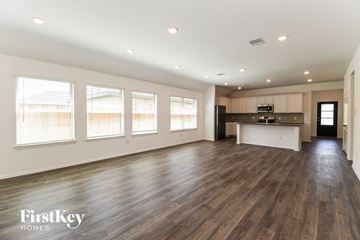 Dickinson house for rent - A spacious room with wooden floors and a kitchen area in the background.
