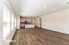 Dickinson house for rent - A spacious room with wooden flooring and a kitchen area in the background.