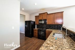 Thornton house for rent - a kitchen with black appliances and granite counter tops and wooden cabinets