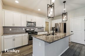 Tucson house for rent - A kitchen with a granite countertop and white cabinets.