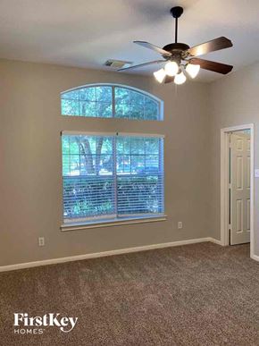 Spring house for rent - a bedroom with a large window and a ceiling fan
