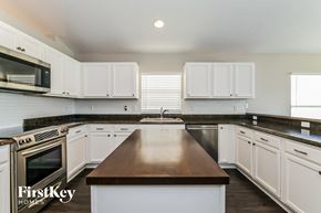 Groveland house for rent - a kitchen with white cabinets and stainless steel appliances and a wooden counter top
