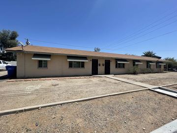 Phoenix apartment for rent - a tan house with a dirt lot and a parking lot