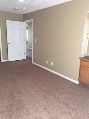 Clinton apartment for rent - a carpeted living room with a door and a kitchen