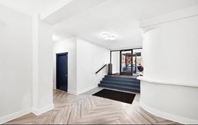 Chicago apartment for rent - A hallway with a black mat on the floor leading to a staircase.
