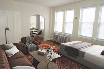 Chicago apartment for rent - A living room with a brown couch and a coffee table with a vase of flowers on it.