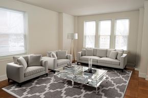 Chicago apartment for rent - A living room with a grey sofa, two armchairs, and a glass coffee table.