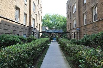 Chicago apartment for rent - A pathway between two buildings with bushes on the sides.