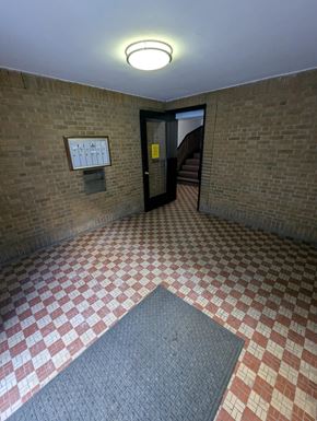 Chicago apartment for rent - A hallway with a brick wall and a checkered floor.