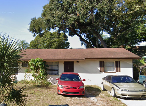 Largo apartment for rent - A red car is parked in front of a white house with a brown roof.