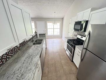 Lawrenceville house for rent - a large kitchen with white cabinets and stainless steel appliances