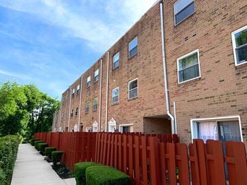 Ardmore apartment for rent - A red fence surrounds a brick building with white windows.