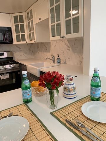 Ardmore apartment for rent - A kitchen counter with a bottle of water, a vase with red flowers, and a plate with a fork and knife on it.