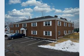 Laconia apartment for rent - a large brick building with a parking lot and snow